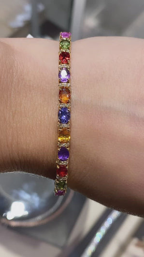 18k yellow gold diamond and multi-colored sapphire bangle bracelet with multi-colored sapphires weighing 4.95 carats total of excellent cut, hue, and even color distribution. Bangle also features round brilliant cut diamonds weighing .42 carats total of F color, VS2 clarity.